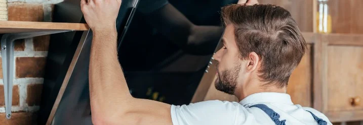 Person montiert Dunstabzugshaube